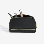 Black cosmetic bag with gold zipper containing makeup items on a white background
