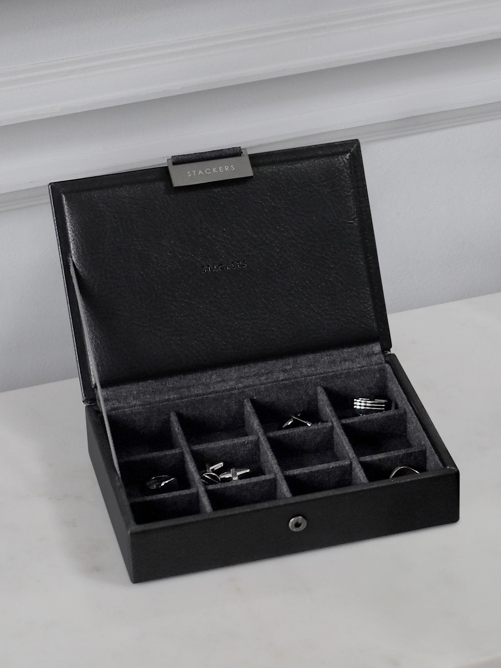 Black jewelry box with compartments on a light gray surface