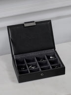 Black jewelry box with compartments on a light gray surface