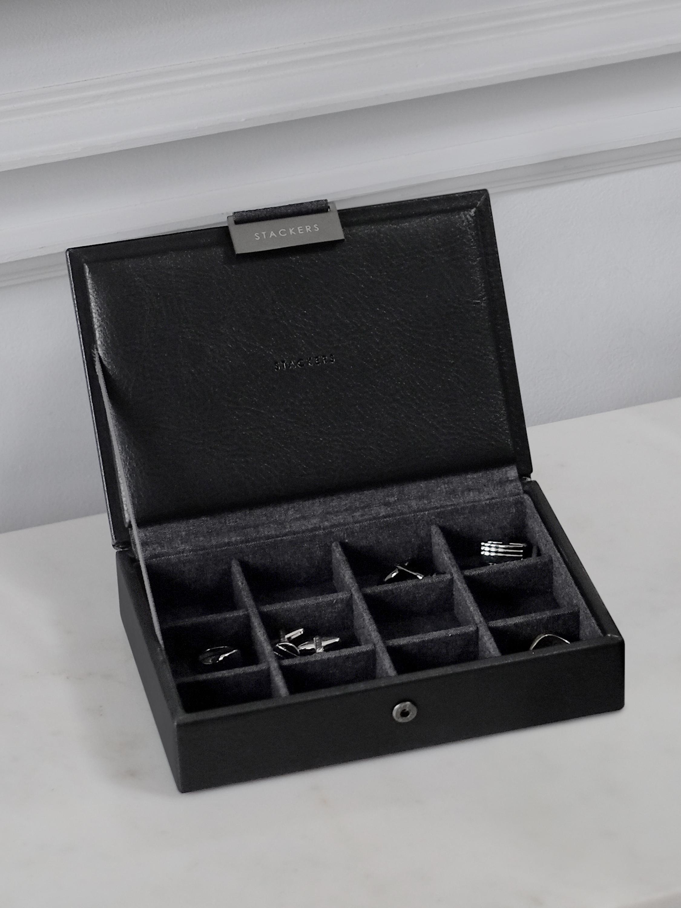 Black jewelry box with compartments on a light gray surface